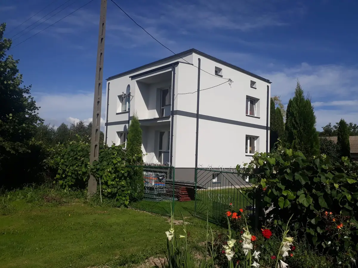 Ten sam dom z daleka, przed nim ogród i drzewa